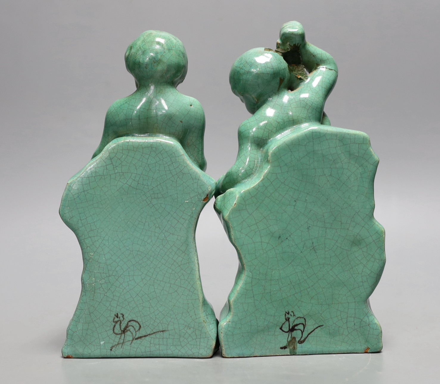 A pair of Cantagalli green monochrome putti figural bookends, 19cms high